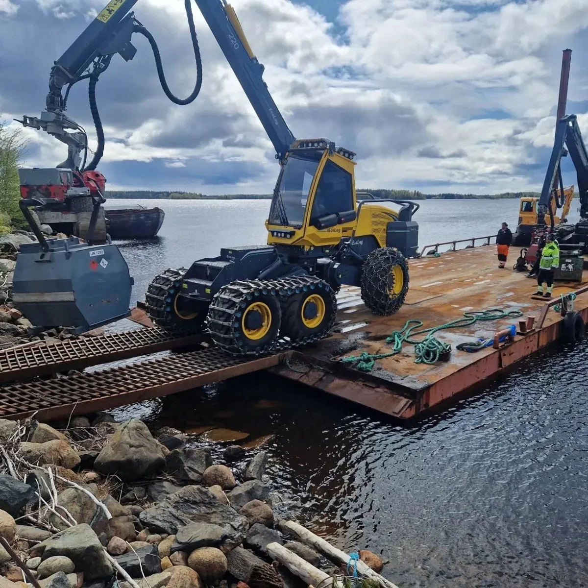 Skördare körs ombord på en pråm vid stranden i Kalix skärgård
